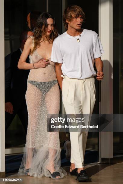 Guest wears a transparent embroidered rhinestones V-neck / long dress, black open toe-cap pumps heels shoes, Jordan Barrett wears gold chain pendant...