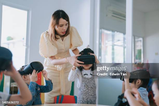 exciting asian chinese preschool students enjoying having fun time with vr google in classroom - classroom wide angle stock pictures, royalty-free photos & images