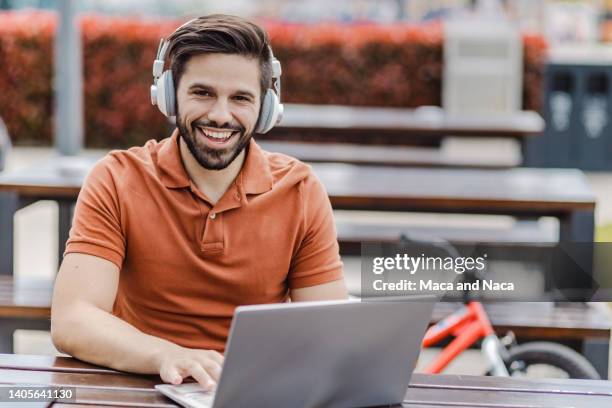 portrait of young bearded man with headphones using a laptop - polo shirt imagens e fotografias de stock