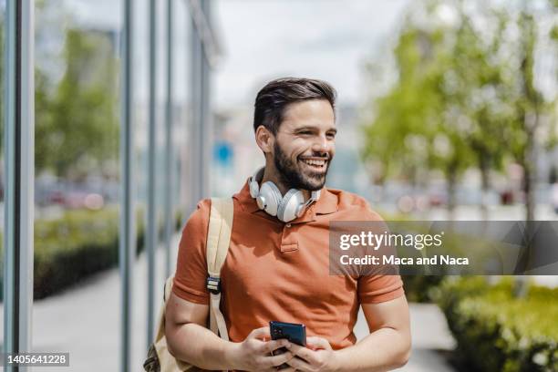 portrait of young smiling man walking on the street - polo shirt stock pictures, royalty-free photos & images