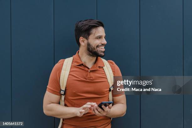 portrait of young smiling man in front of the black wall - polo shirt stock pictures, royalty-free photos & images