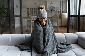 Latina female shiver at freezing flat in warm cap blanket