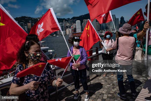 People hold Chinese national and Hong Kong flags during a celebration in front of the Victoria Harbour promenade ahead of the 25th anniversary of...