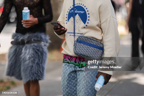 Guest seen wearing a creme blue logo Adererror knit sweater/pullover, a blue leather log crossbody bag from Le Tanneur and a light blue logo Louis...