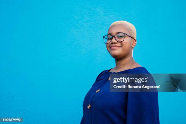 portrait of young woman in blue background - gay person color background stock pictures, royalty-free photos & images