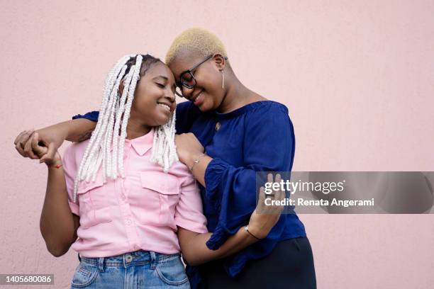 lesbian couple smiling in  pink background - gay person color background stock pictures, royalty-free photos & images