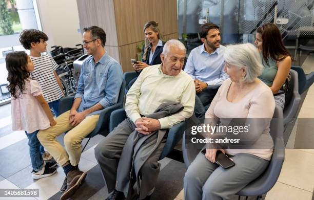 group of people at the hospital sitting in the waiting room - patients in doctors waiting room stockfoto's en -beelden