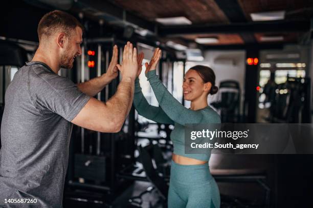 female and fitness trainer friends - hi five gym stockfoto's en -beelden