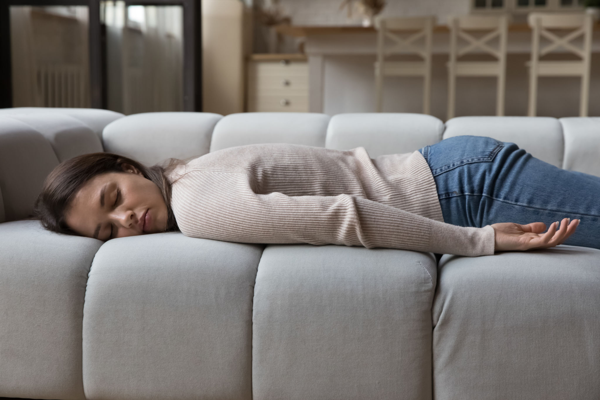 Tired woman resting on spacious sofa in home living room Tired woman resting on spacious sofa in home living room