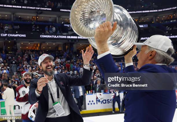 Stanley Kroenke of the Colorado Avalanche passes the Stanley Cup to Josh Kroenke following the series winning victory over the Tampa Bay Lightning in...