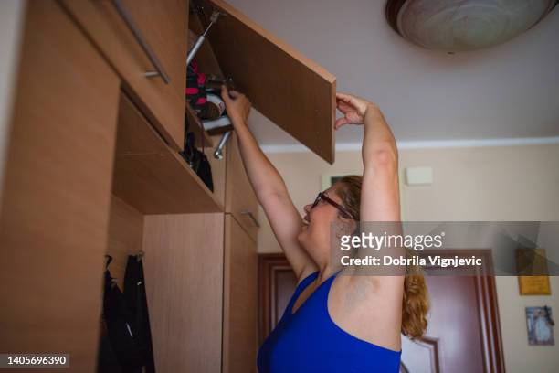 close up of a woman opening upper closet and taking out sports shoes - open workout stockfoto's en -beelden