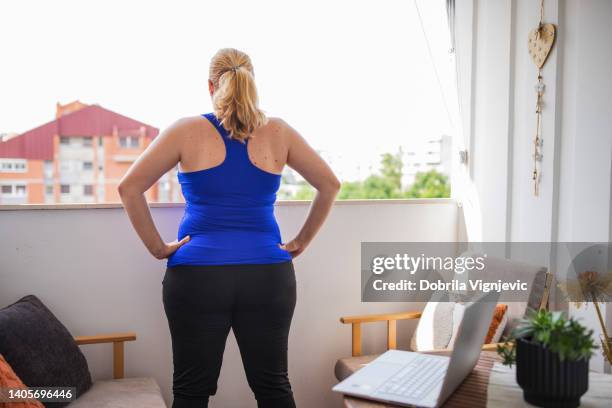 rear view of a woman exercising on balcony - yoga pants stock pictures, royalty-free photos & images