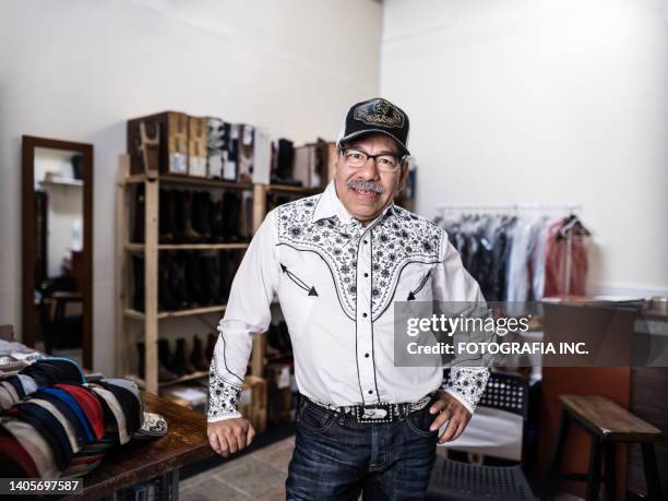 portrait of mature latin store owner dressed as mexican cowboy - western shirt stockfoto's en -beelden