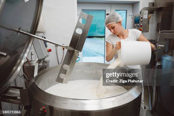 woman pouring milk in a large pot - dairy factory worker stock pictures, royalty-free photos & images