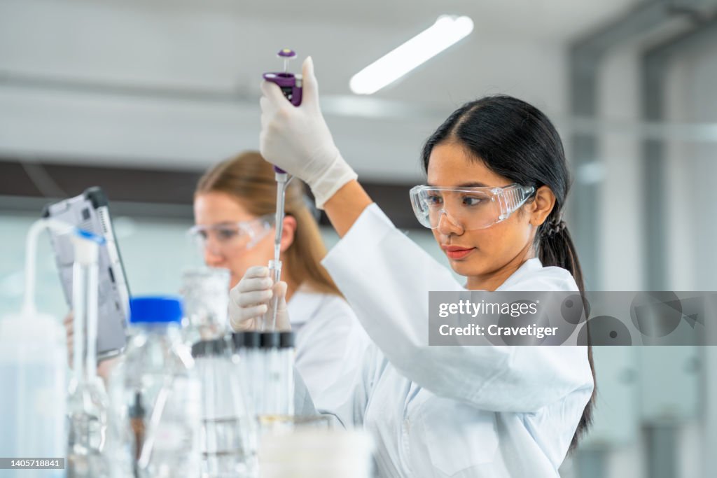 Biologists put chemical liquid with the pipette in a test tube inside a laboratory. Research and Development concepts.