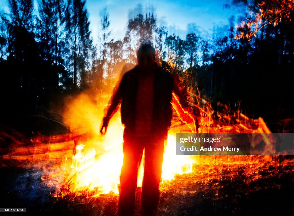 Glowing person, fire at night in dark forest