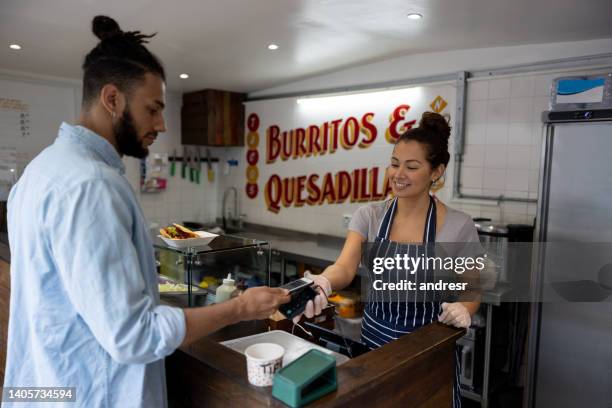 cliente que realiza un pago sin contacto en un pequeño restaurante mexicano - paid palabra en inglés fotografías e imágenes de stock