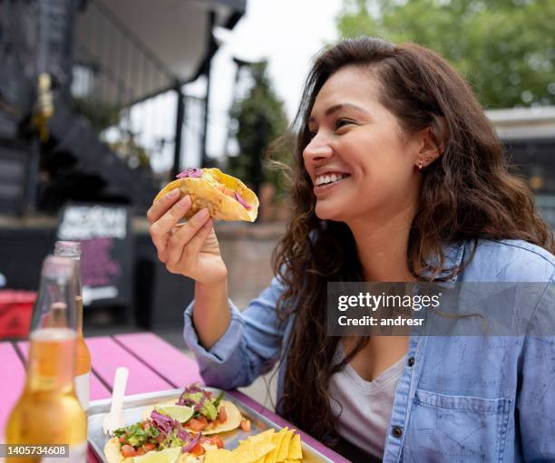 happy woman eating tacos at a restaurant - taco stockfoto's en -beelden