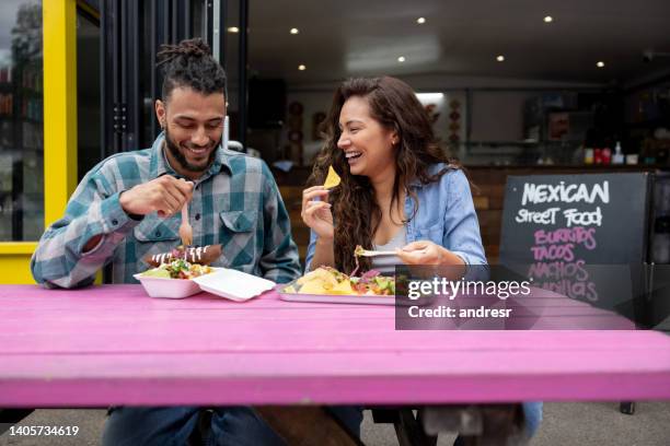 loving couple looking happy eating tacos at a mexican restaurant - mexican food imagens e fotografias de stock