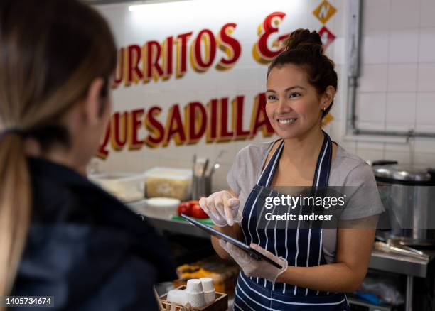 woman working at a restaurant and using a tablet to take the customerâs order - fast food register stock pictures, royalty-free photos & images