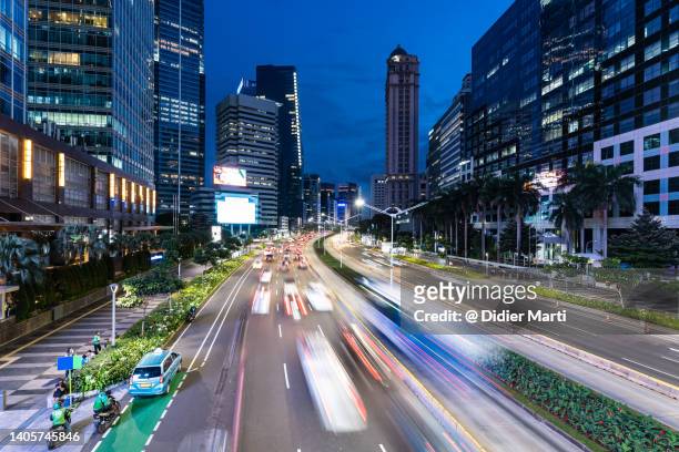 jakarta, indonesia: traffic captured with blurred motion rushing along the sudirman avenue in the heart of jakarta business and financial district in indonesia capital city. - jakarta stock pictures, royalty-free photos & images