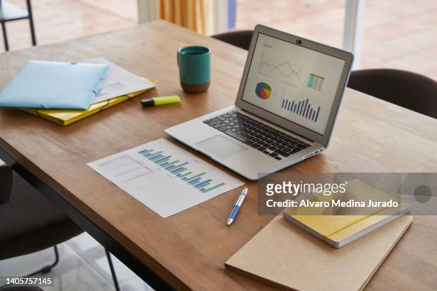 desktop in the living room of a house with laptop and documents ready to work remotely. - working from home desk stock pictures, royalty-free photos & images