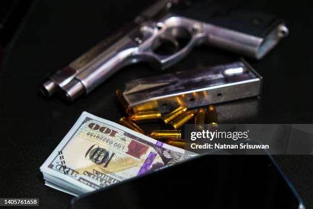 gun with bullets lying on the table. money on black background. criminal problems. dollars. - organized crime stock-fotos und bilder