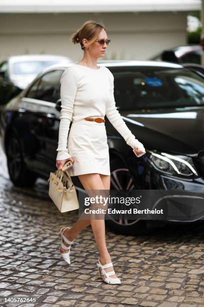 Guest wears white sunglasses, a white latte long sleeves t-shirt, a white latte denim short dress with a brown shiny leather belt, a white latte...