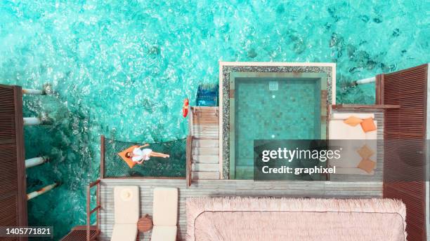 beautiful woman lying on hammock over ocean in maldives - atol stock pictures, royalty-free photos & images