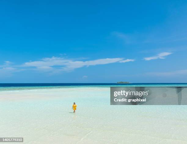 beautiful woman walking in transparent turquoise sea - infinity loop stockfoto's en -beelden