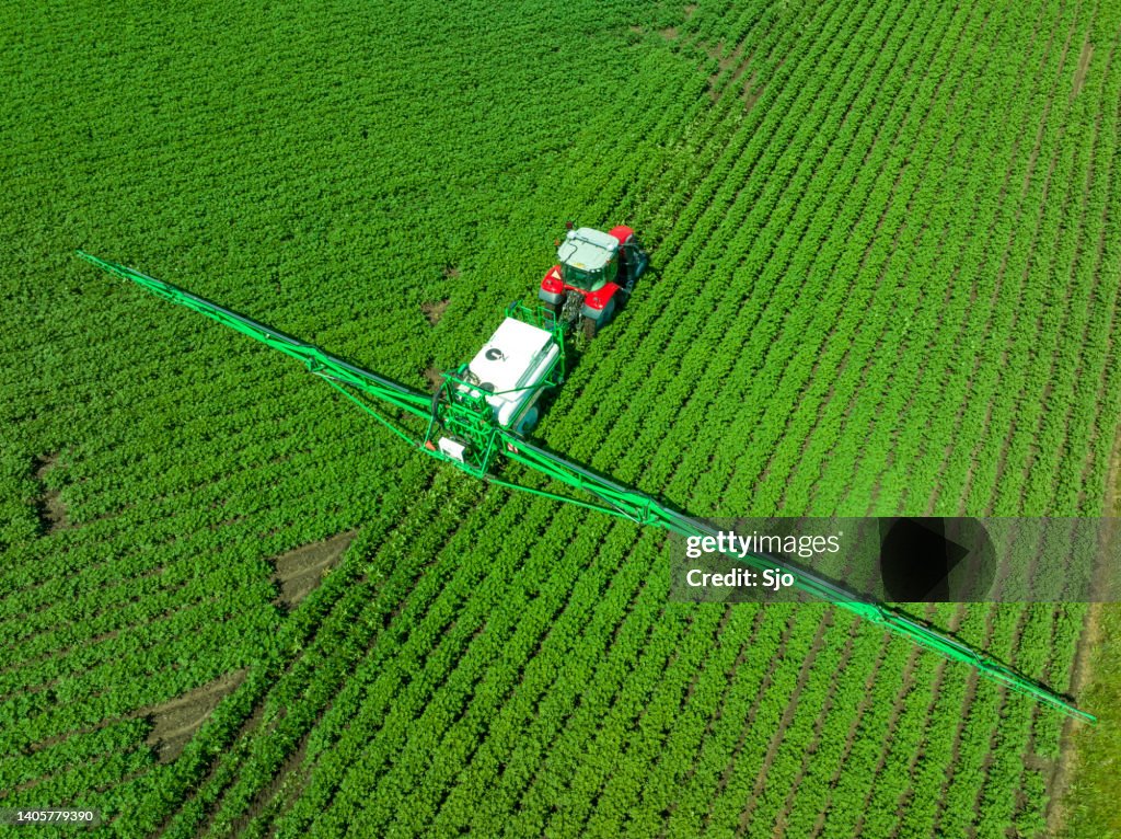 Agricultural crops sprayer spraying on a field during springtime