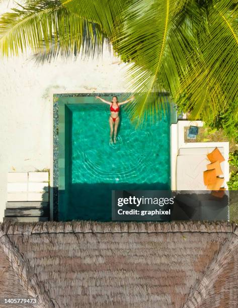 beautiful woman enjoying pool under palm tree - villa pool stockfoto's en -beelden