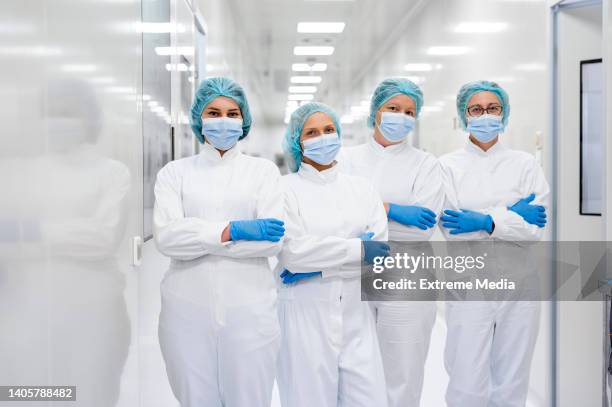 fully equipped female workers standing in the hallway of the drug manufacturing - cleanroom stock pictures, royalty-free photos & images