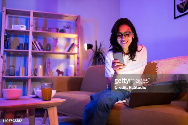 portrait of a young woman freelancing and using smartphone - neon lighting smiling stock pictures, royalty-free photos & images