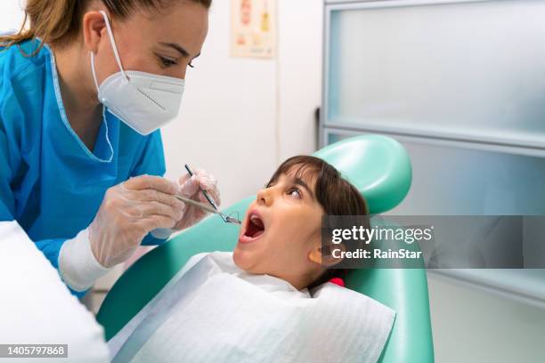 dentist at the dentist's office examining the girl's teeth - fluor stockfoto's en -beelden