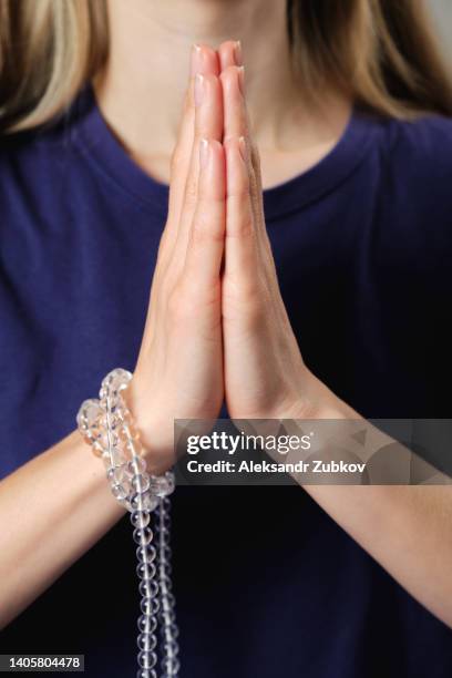 transparent crystal rosary in the hands of a young woman, she practices yoga. the girl's hands are folded in a prayer gesture namaste. religious symbol of the concept of faith, prayer, meditation and mantra repetition. - prayer pose greeting fotografías e imágenes de stock