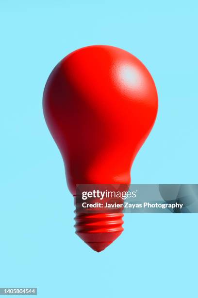 red incandescent light bulb on blue background - red light bulb stock pictures, royalty-free photos & images