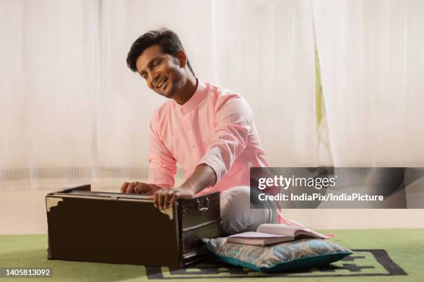 portrait of young man playing harmonium at home - harmonium stock-fotos und bilder