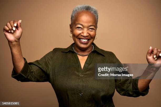 portrait of happy african american senior woman standing with raised arms - senior woman studio ストックフォトと画像