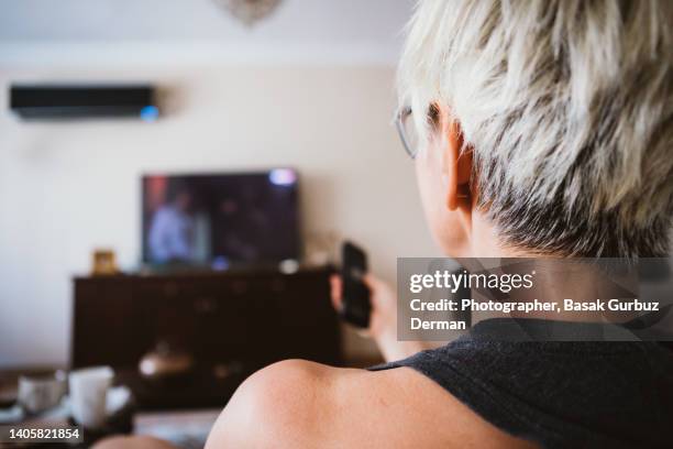 a woman watching tv, using remote control - head and shoulders fotografías e imágenes de stock