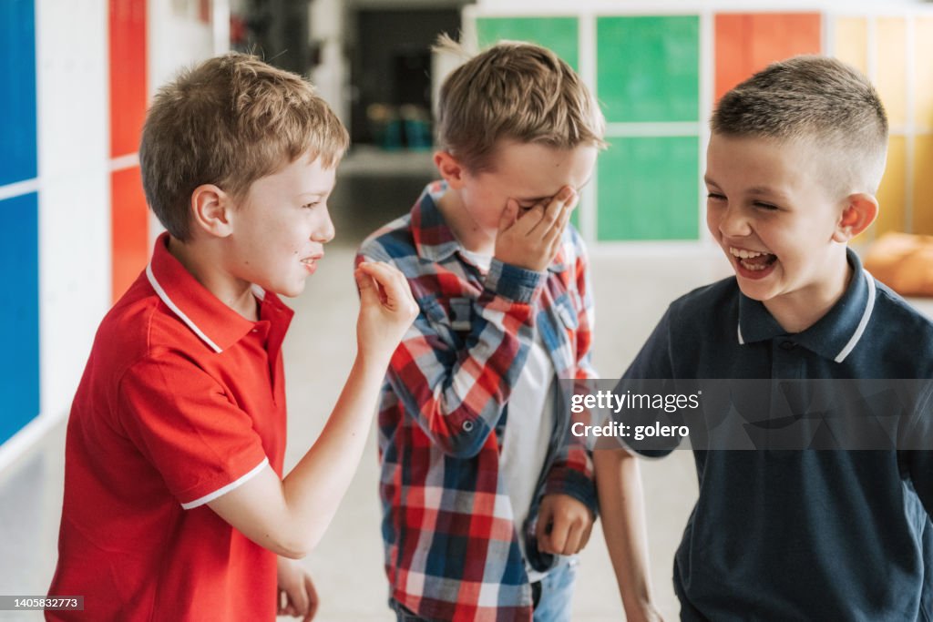 Tres escolares divirtiéndose juntos en el pasillo de la escuela