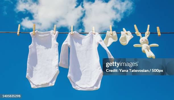 white baby clothes dry on a rope selective focus - baby clothing stock pictures, royalty-free photos & images