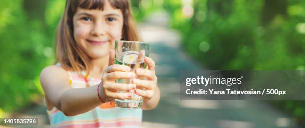 a child drinks water from a glass on the nature selective focus - girl filling water glass stock pictures, royalty-free photos & images