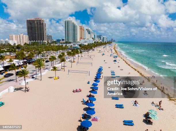 Aerial view of Miami Beach shows coastline and blue umbrellas on sandy beach of Florida.