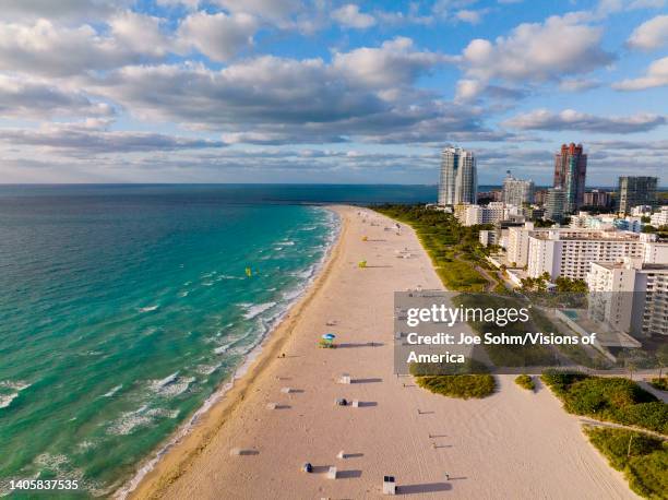Aerial view of Miami Beach shows coastline and blue umbrellas on sandy beach of Florida.