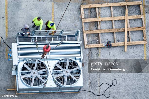 Miami Beach, Florida, construction crane placing HVAC AC air conditioner cooling tower onto rooftop.