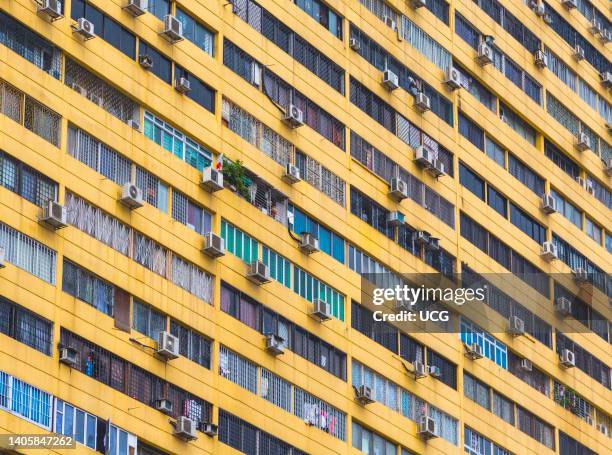 Multiple air conditioner units on exterior of apartment building, Republic of Singapore. Air conditioners emit greenhouse gases known as...