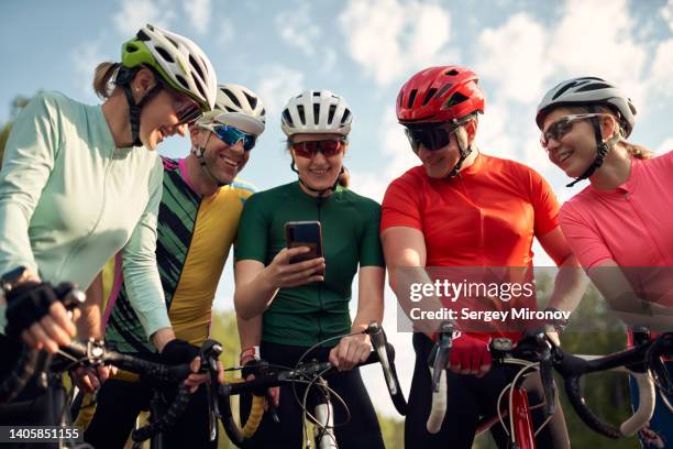 group of friends with road bicycles looking at smartphone - straßenradsport stock-fotos und bilder