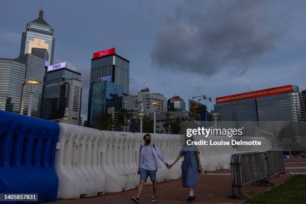 Pedestrians walk past water barrier near the Hong Kong Convention and Exhibition Center ahead of the handover anniversary on June 29, 2022 in Hong...