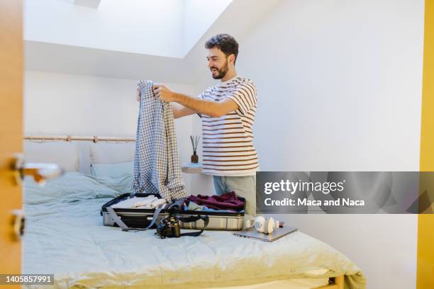 wide shot of excited man packing his clothes in a suitcase. finally vacation! - escape the room event stock pictures, royalty-free photos & images